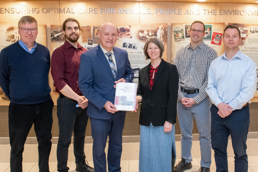 Dr. Michelle Evason presents a copy of Infectious Diseases of the Dog and Cat: A Color Handbook to Dean Greg Keefe while other contributors from AVC look on.