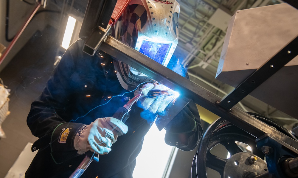 a technician wearing a welding helmet using welding equipment