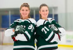 Two female hockey players stand back to back