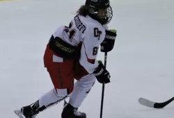a female hockey player skates up the ice with a puck