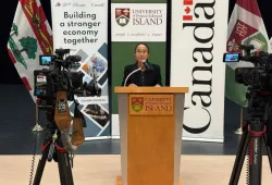 Dr. Beibei Jia, Assistant Professor, Epidemiology, AVC, speaks at the news conference announcing funding for shellfish health research and resilience projects. Photo of a woman standing at a podium flanked by video cameras