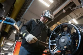 a welder wearing a protective helmet adjusting a steel wheel