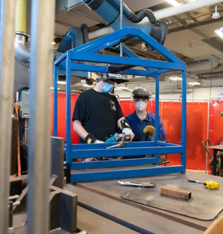 an instructor assisting a student with welding