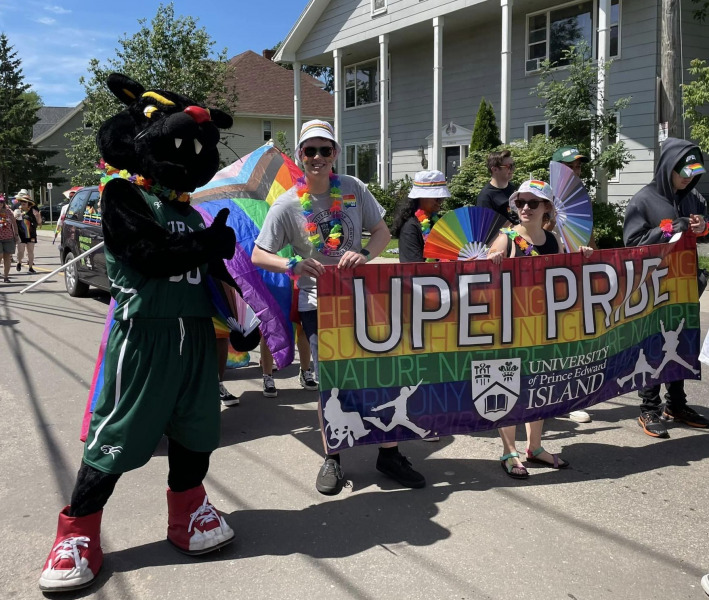 UPEI’s mascot, Pride and members of the UPEI Student Union walk with the UPEI banner in the 2023 Pride Parade in Charlottetown