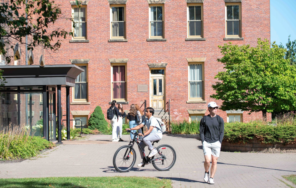 photo of person biking and others walking on a brick pathway on campus