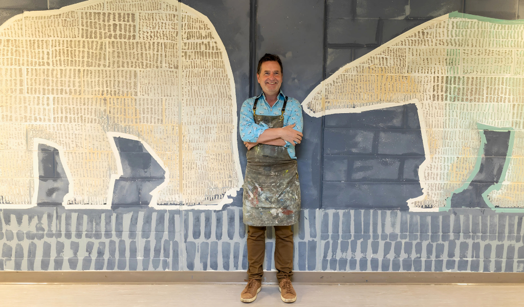 Artist Christopher Griffin stands in front of his mural in the AVC Polar Bear Lounge