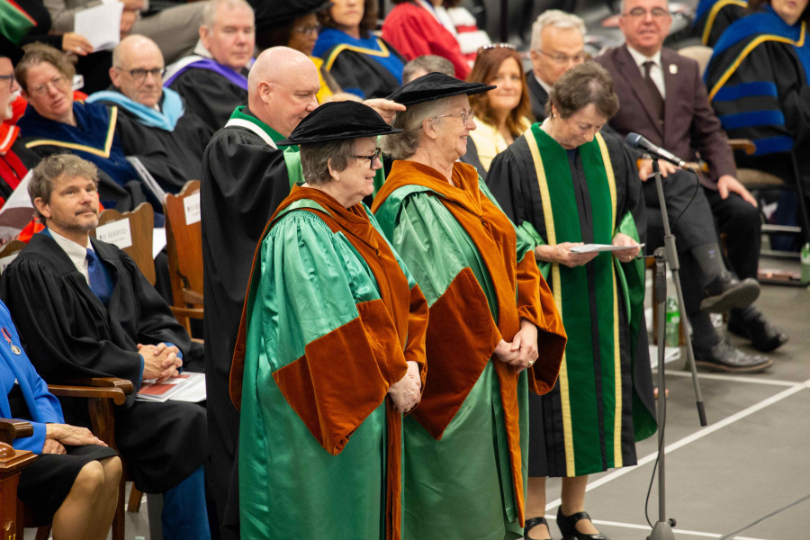 Photo of a man placing a hat on a woman at a convocation ceremony