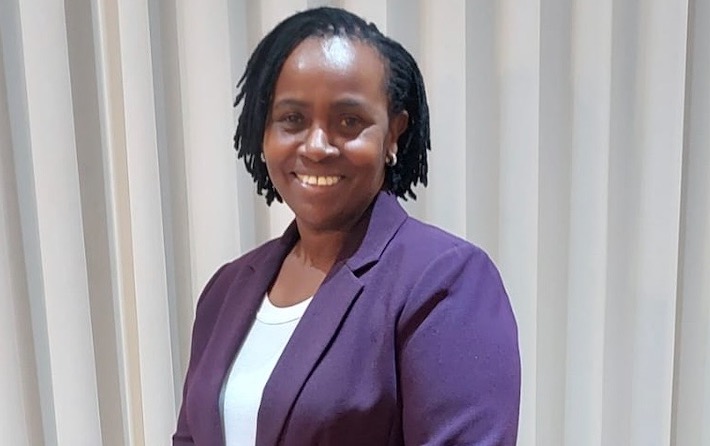 Photo of smiling woman standing against a curtain background.