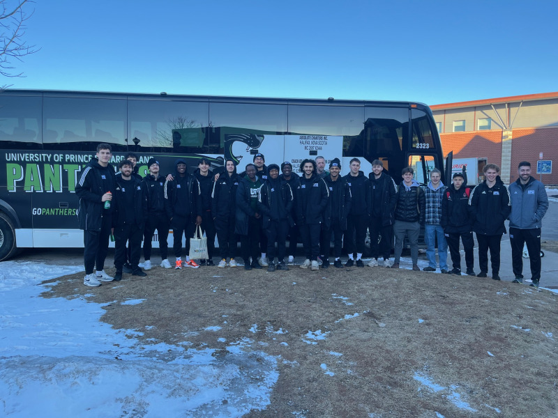 photo of team in front of a branded motor coach bus