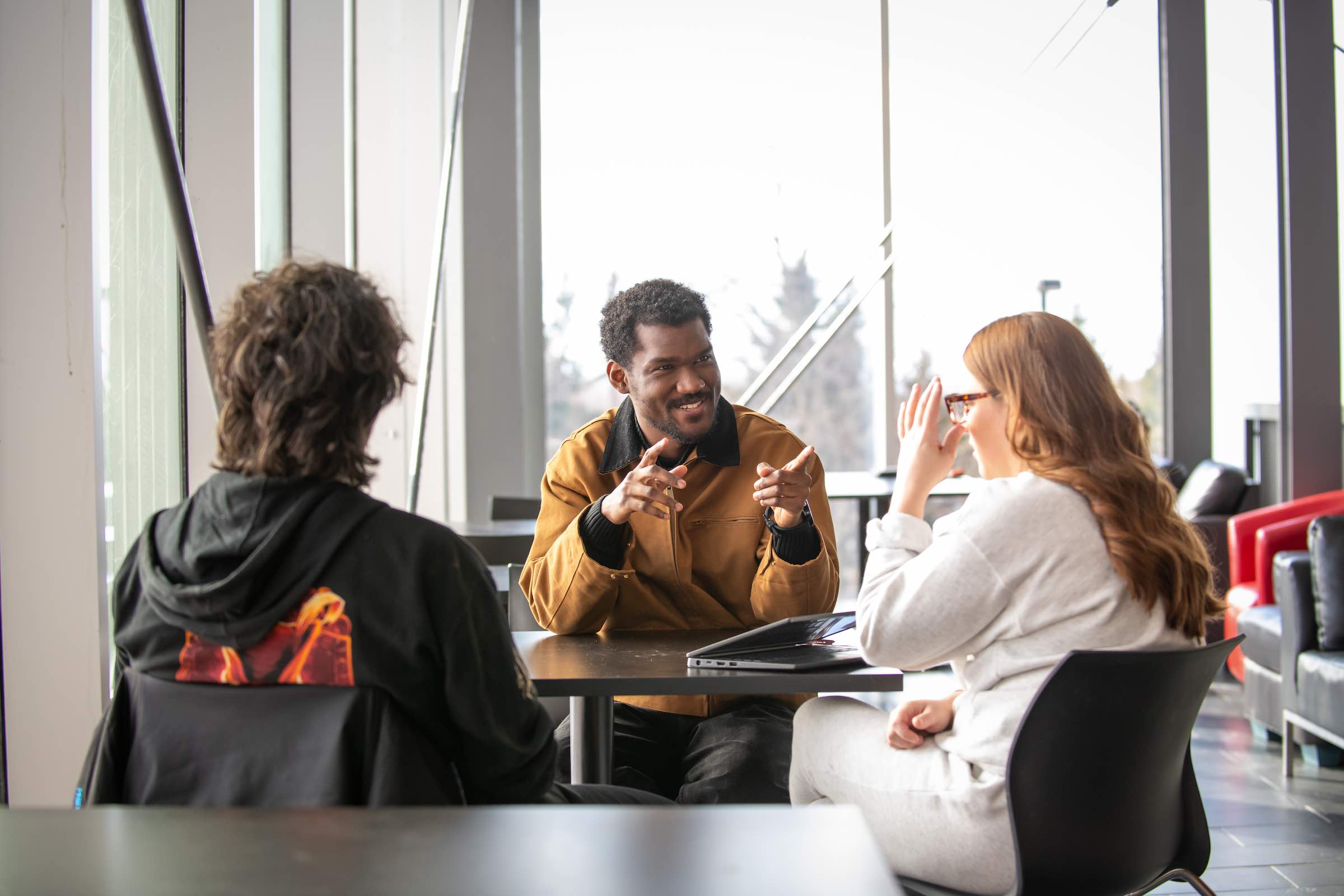 three students talking at a small table