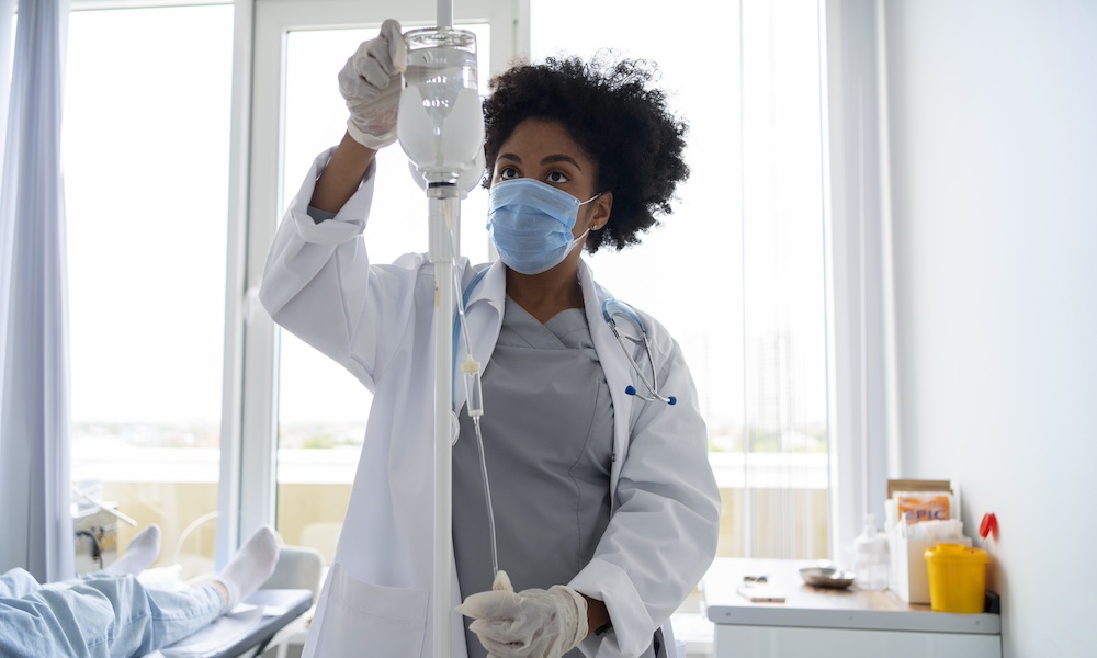 a doctor wearing a mask adjusting an IV 