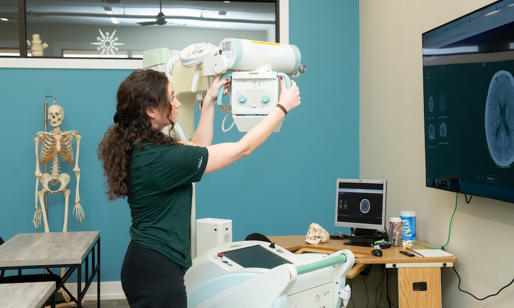 a radiographer adjusting equipment in a clinical training lab