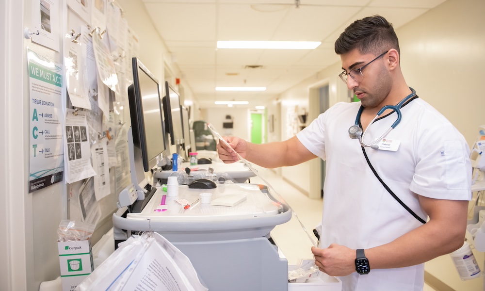 UPEI nursing student Gabriel reading a chart at the Queen Elizabeth Hospital