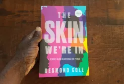A photo of a copy of The Skin We're In held by a hand