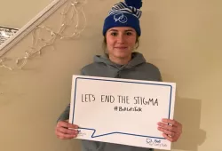 photo of young woman wearing toque and holding thought bubble placard