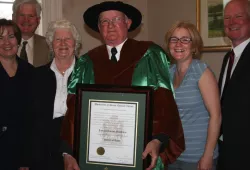 photo of man in academic regalia surrounded by his family