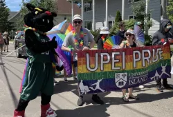 UPEI’s mascot, Pride and members of the UPEI Student Union walk with the UPEI banner in the 2023 Pride Parade in Charlottetown