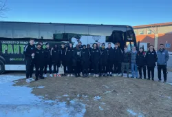 photo of team in front of a branded motor coach bus