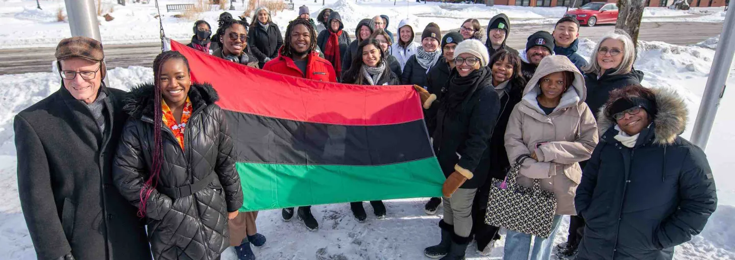 a large group pf people behind the red, black, and green Pan-African flag