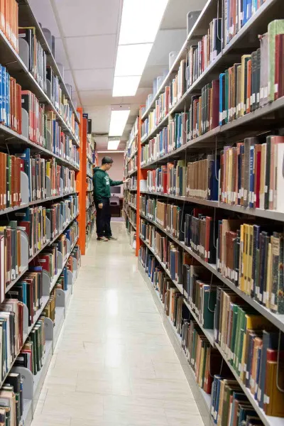 a student looking at books in the Robertson Library stacks