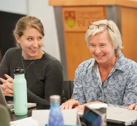 a smiling professor speaks to students in a classroom