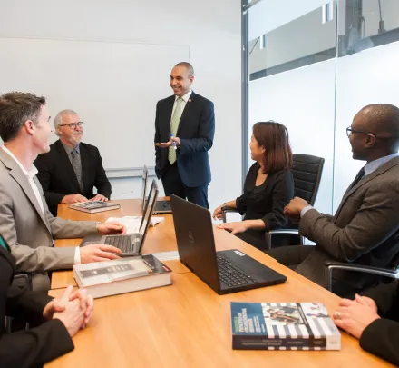 professor lectures to students in boardroom