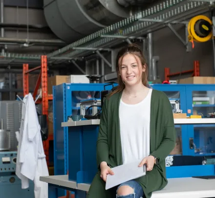 a female engineering student sitting on a desk in a project bay