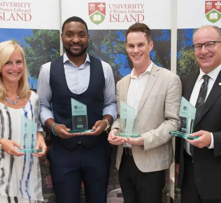 four UPEI distinguished alumni pose with awards