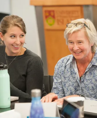 a smiling professor speaks to students in a classroom