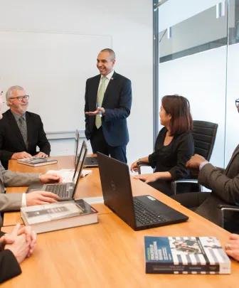 professor lectures to students in boardroom