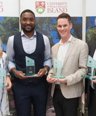 four UPEI distinguished alumni pose with awards