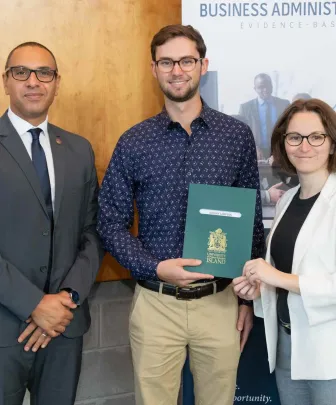 two faculty of business professors presenting a student award