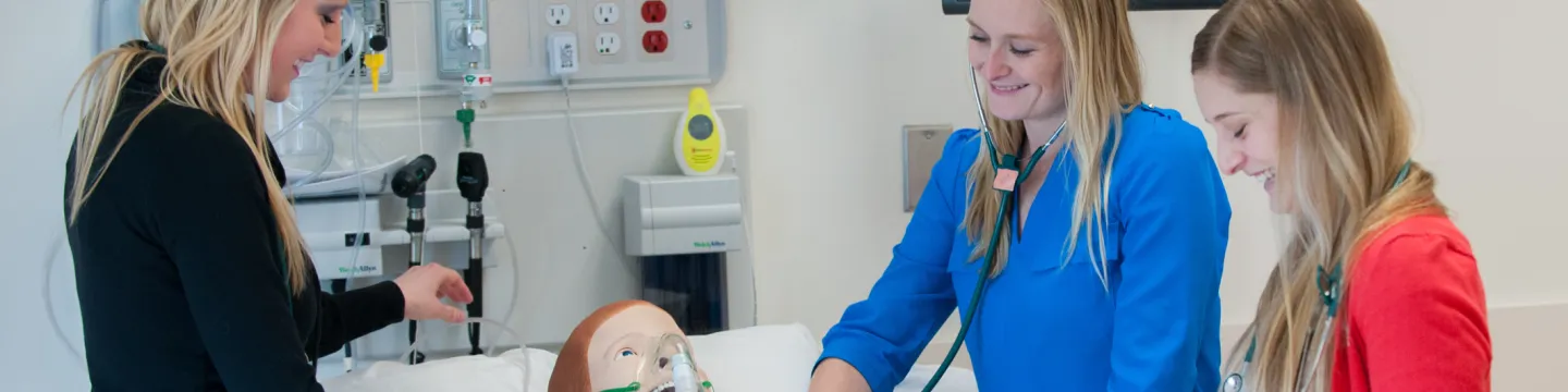 three nursing students with clinical mannequin