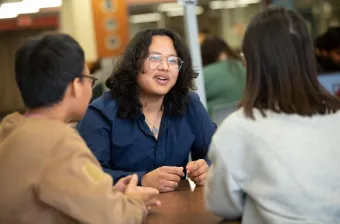 a UPEI student talking to two friends in the Robertson Library